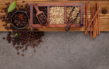 Various of roasted coffee beans in wooden box with manual coffee grinder setup on shabby wooden background.