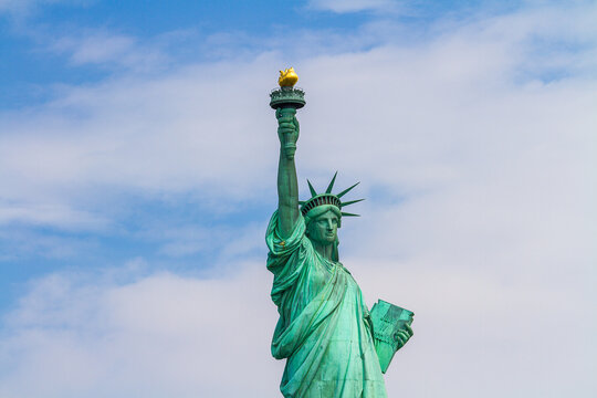  A close up image of the Statue of Liberty on blue and cloudy sky background