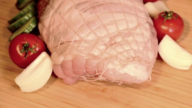 Schweinerollbraten mit Zwiebeln, Tomaten und Gurken dekoriert