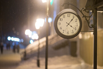 A big old clock on a city street in winter.