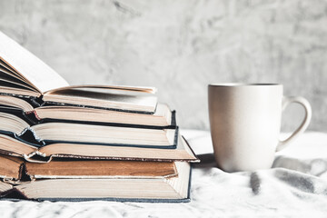 Stack of opened books with a cup of coffee in bed