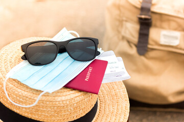 Passport and tickets, mask. Summer trip. Sunglasses, hat and backpack. Waiting in Railway station...