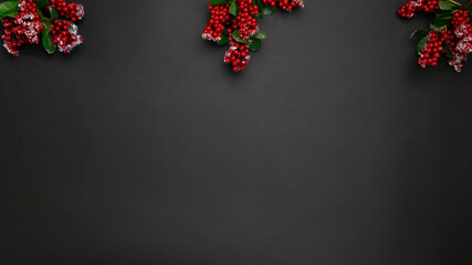 Christmas branches around the edges of a black background. Red berries on pattern background