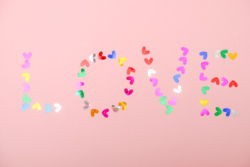 Love word made from small hearts on a pink background. Valentine's day and International women's day greeting card.