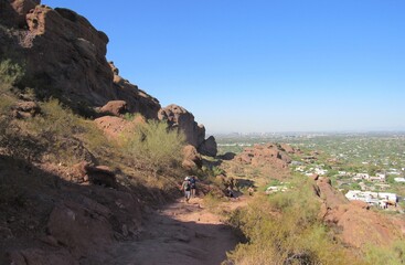 View on the Camelback Mountain hiking trail with some unrecognizable people on the path on a sunny day with blue sky in Phoenix, Arizona