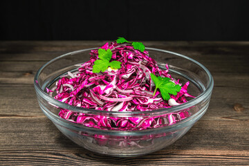 Chopped red cabbage in a glass dish on a wooden table background