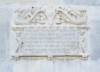 Latin inscription embellished with mythological figures carved in stone on the facade of the cathedral of Como.Lombardy, Italy.