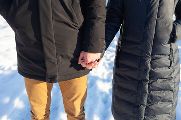 Young guy and girl in black jackets holding hands in winter