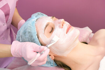 Young woman with a cleansing mask on her face in the salon
