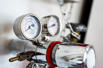 Closeup of pressure manometer measuring gas pressure, industry background, selective focus, pipes and valves in the chemistry laboratory