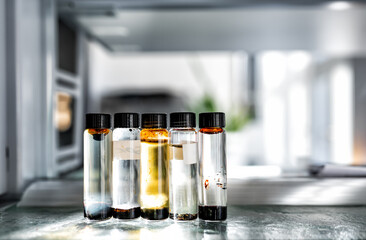 Closeup of laboratory glassware filled with orange and brown oily liquids, science and research background, selective focus