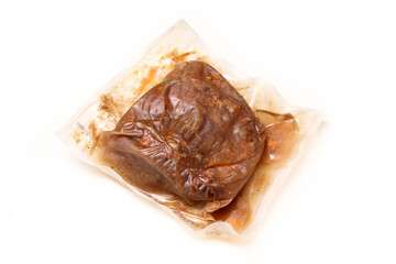 The semifinished pulled pork meat in the plastic foil prepared by the sous vide process isolated on a white background. 