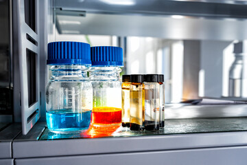 Closeup of laboratory glassware filled with blue and orange liquids, science and research background, selective focus
