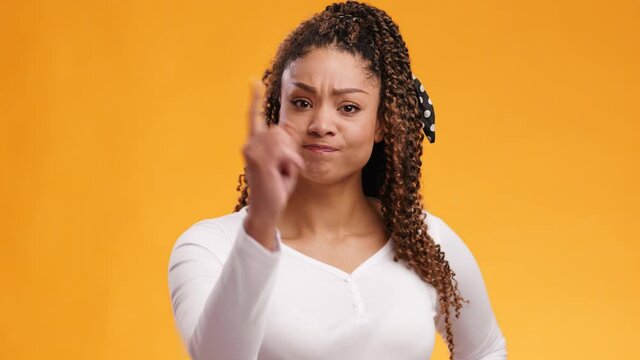 Young displeased african american woman pointing finger to camera, blaming expression, orange studio background