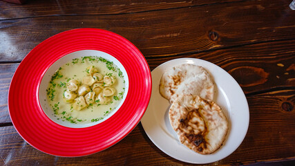 Red plate with broth and dumplings on the table