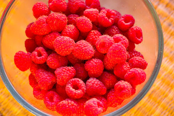 Red ripe and juicy raspberry in a glass bowl