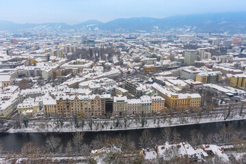 Cityscape of Graz with Mur river and historic buildings rooftops in winter with snow, in Graz, Styria region, Austria