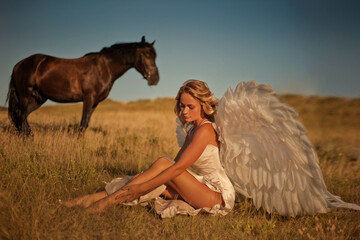 A girl on a horse with white angel wings at a horse