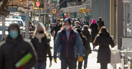 Crowd of people walking street wearing masks
