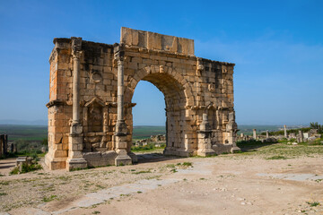 Arch of Caracalla (Triumphal Arch) at the Archaeological Site of Volubilis under a blue sky,...