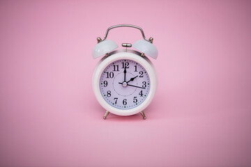 White alarm clock on pink background.Time concept.