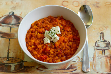 Red lentils pottage with cheese and parsley in a white bowl