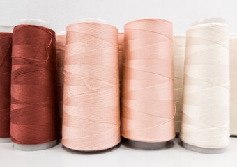 sewing threads in bobbins in three shades from brown to white