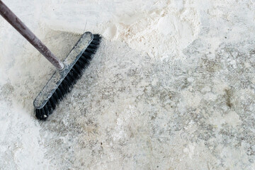 Dirty dusty old broom on the grunge floor in the corner of a renovated room 
