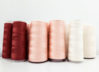 Fototapeta na wymiar sewing threads in bobbins of three colors changing from brown to white