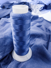 A spool of thread for embroidery in the color of the fabric as a background