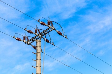 Electricity distribution in Czech Republic. Electricity poles in a row. High voltage poles in the cloudy blue sky. Industrial landscape.