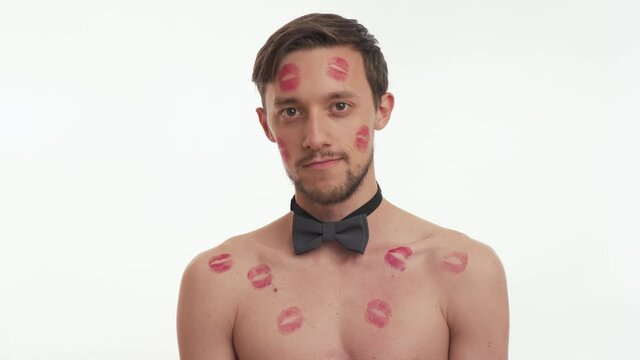 Attractive lovely man with kiss imprints or marks look at the camera isolated on white wall background. Young nice Caucasian guy with grey bow tie speak. Romantic concept of Valentine's day close up.