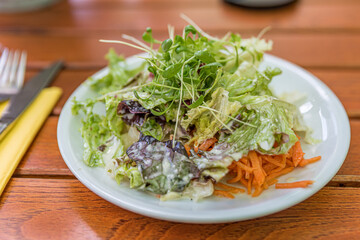 Green vegan salad from green leaves mix and vegetables. Top view on wooden table.
