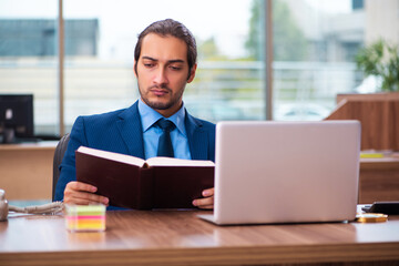 Young male employee reading book in the office