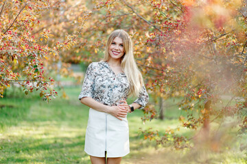 Young woman in full height in a beautiful rose garden in spring