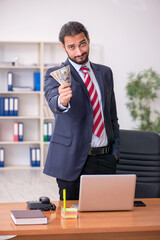 Fototapeta premium Young male employee holding banknotes in the office