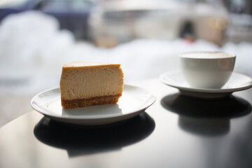 caramel cheesecake with cappuccino on a black table