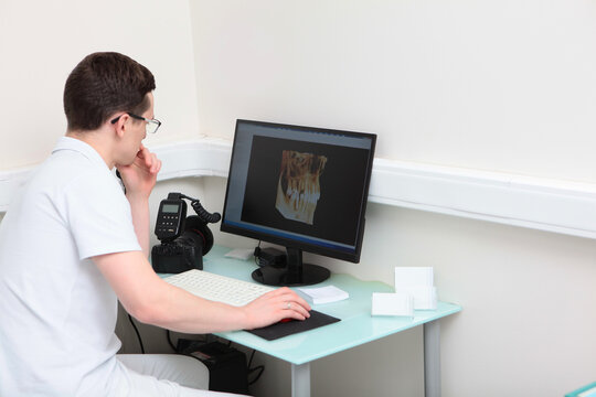 Dentist doctor examines images of teeth on a computer screen. Modern dentistry. Volumetric image. Photo camera on the desktop. Photo in the interior.