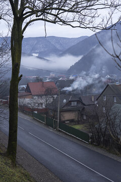 Mountain Village In The Fog. Smoke Coming Out Of The Pipes Of The Stove Heating