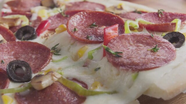 A slice of cheese, olive and pepper pizza is served. Salami pizza slice is taken by hand. Hot melted cheese yawning, close up. Fast food concept. 