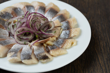 pieces of salted fish with pickled onions. Scandinavian herring appetizer on a white plate