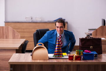 Young male employee celebrating Christmas at workplace