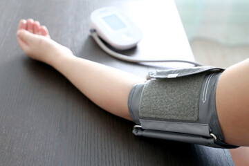 Fototapeta premium Woman measuring blood pressure with electronic digital tonometer, female hand close up. Health care, hypertension and cardiology concept