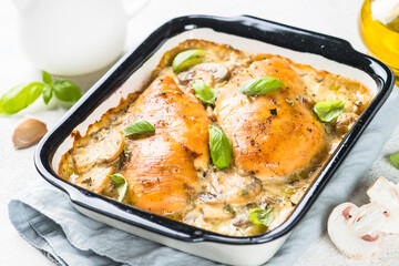 Baked chicken breast with mushrooms in cream sauce on white kitchen table.