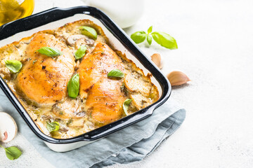 Baked chicken breast with mushrooms in cream sauce on white kitchen table.