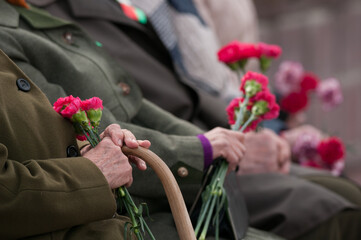 
veterans holding flowers at the Victory Day on May 9 in the Republic of Belarus and the Russian Federation.
