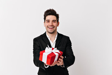 Studio shot of smiling man with birthday gift. Guy in black jacket celebrating valentine's day.