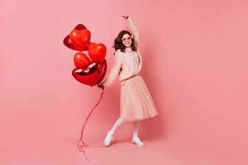 Good-looking girl with party balloons expressing sincere emotions. Studio shot of cute ginger model...