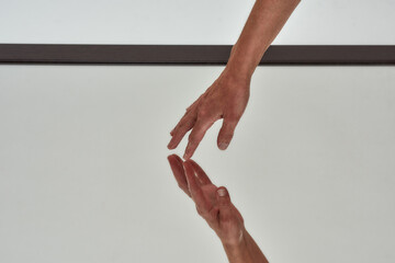 Close up shot of female hand touching reflective surface of mirror on the floor isolated over light...