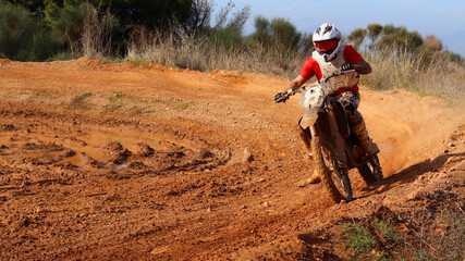 Professional dirt bike motocross rider performing stunts in extreme mud terrain track